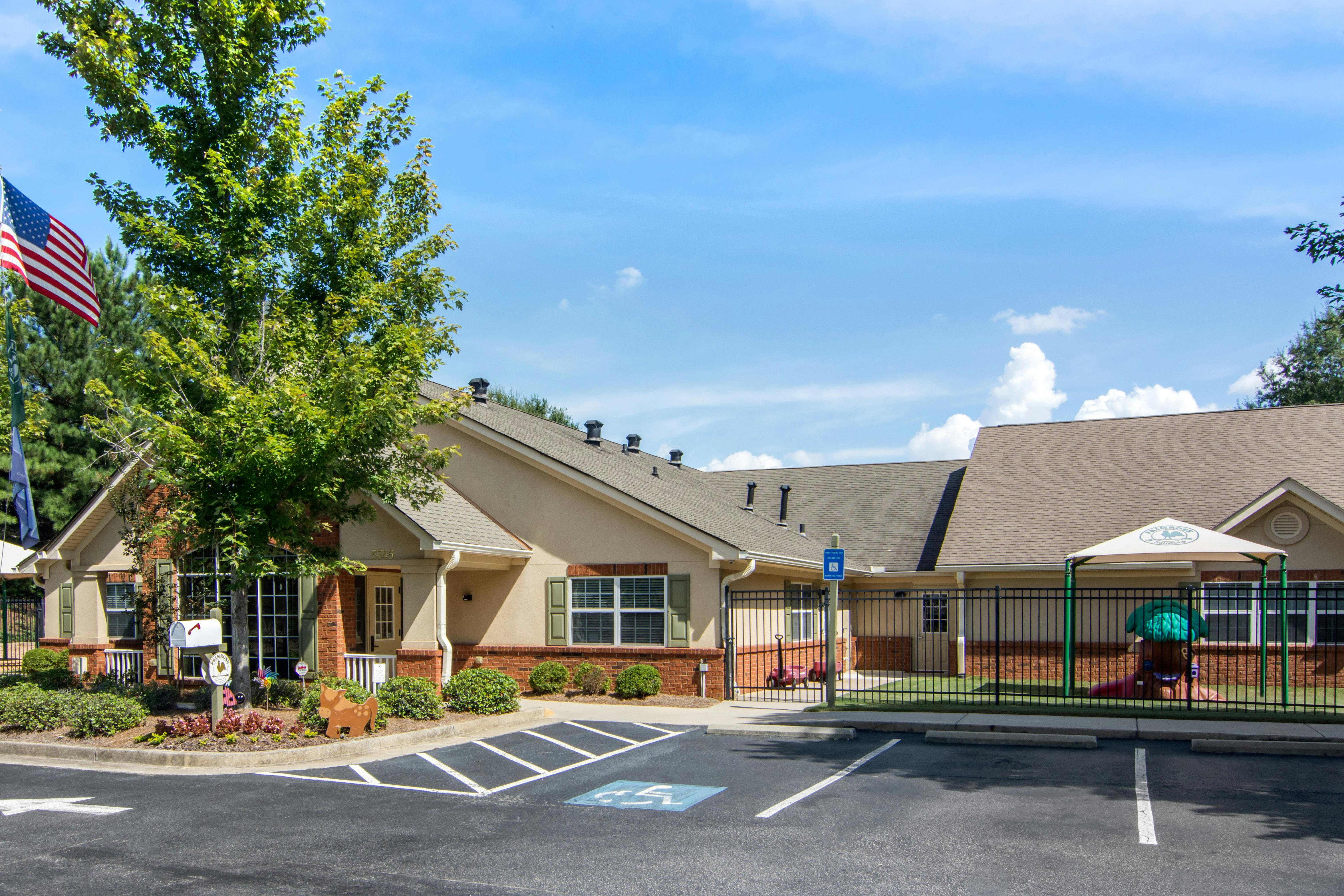 Exterior view of a building with an American flag, trees, and a playground