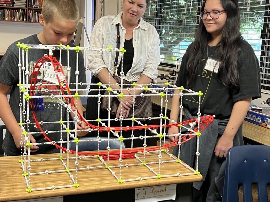 Three people observing a roller coaster model