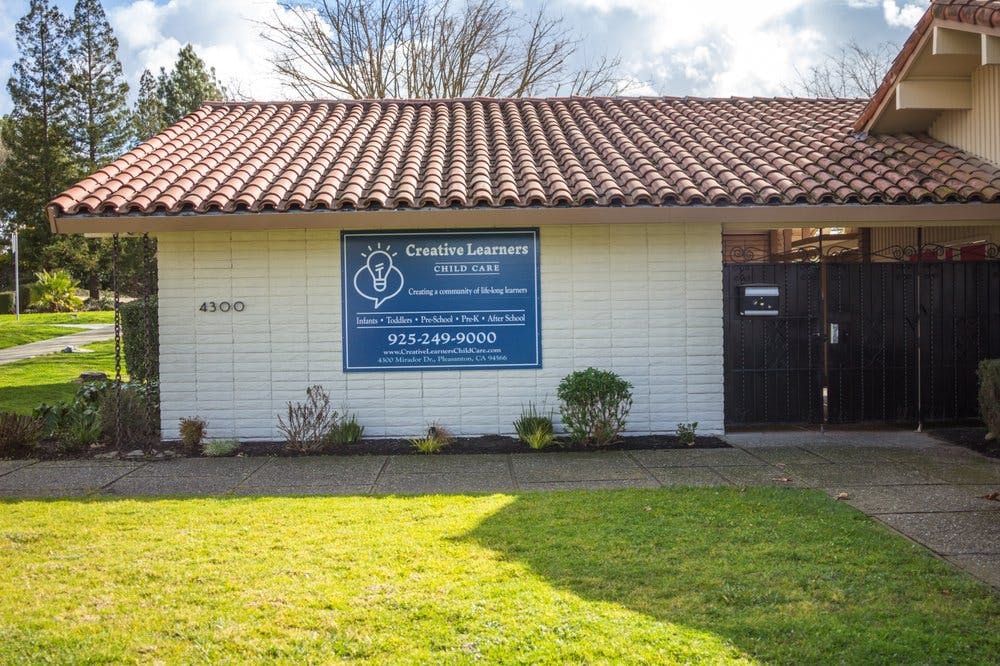 Building with a red tile roof and a blue sign that says "Creative Learners"