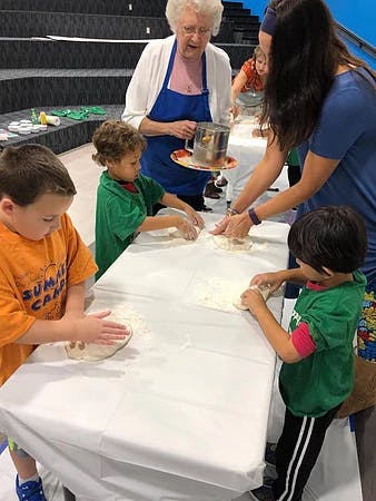 Adults and children making dough at a table