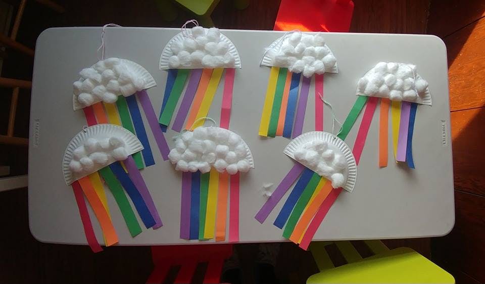 Crafts of clouds made from cotton balls with colorful paper strip rainbows