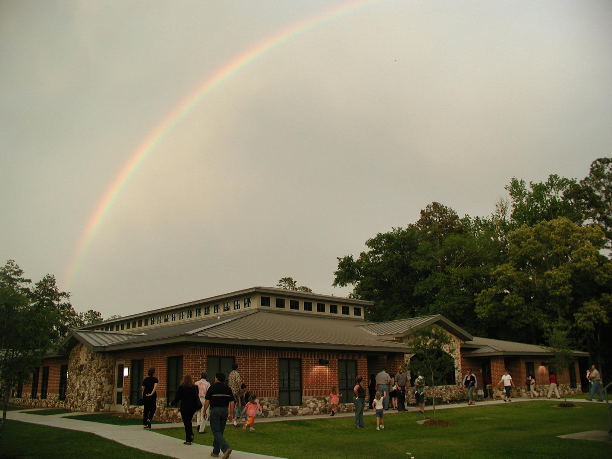 Rainbow over a building with people gathered outside