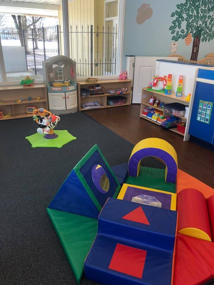 Indoor play area with soft play equipment and shelves of toys