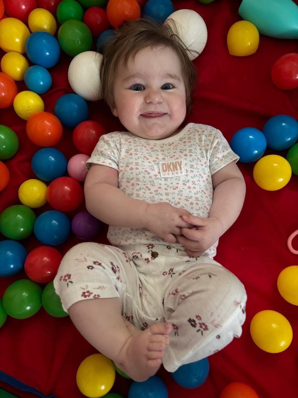 Child lying on back surrounded by colorful balls