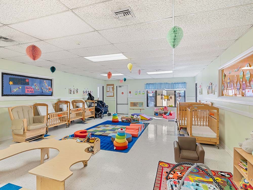 daycare or nursery room with cribs, play mats, and small tables