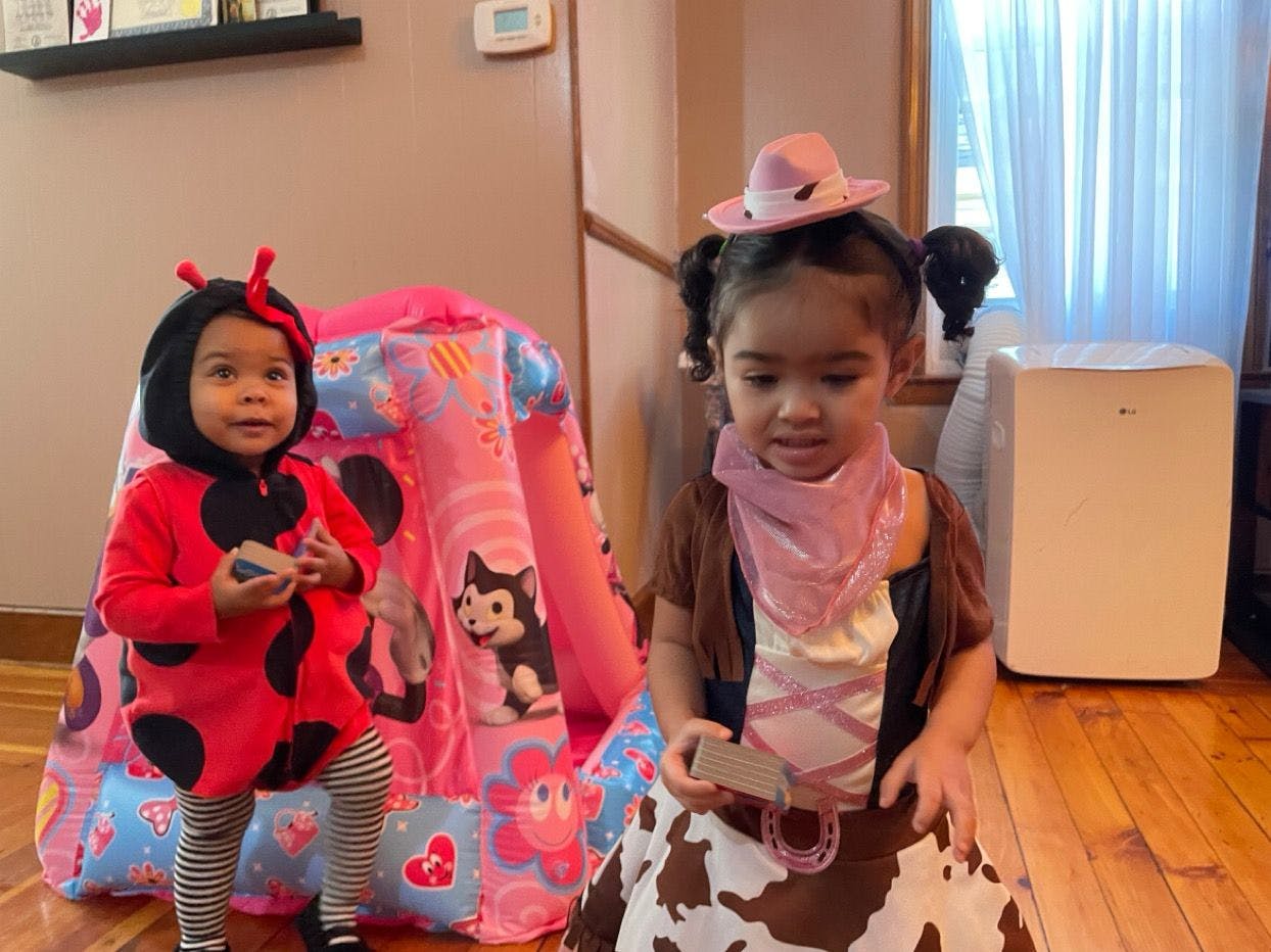 Two children in costumes, one in a ladybug costume and one in a cowgirl costume