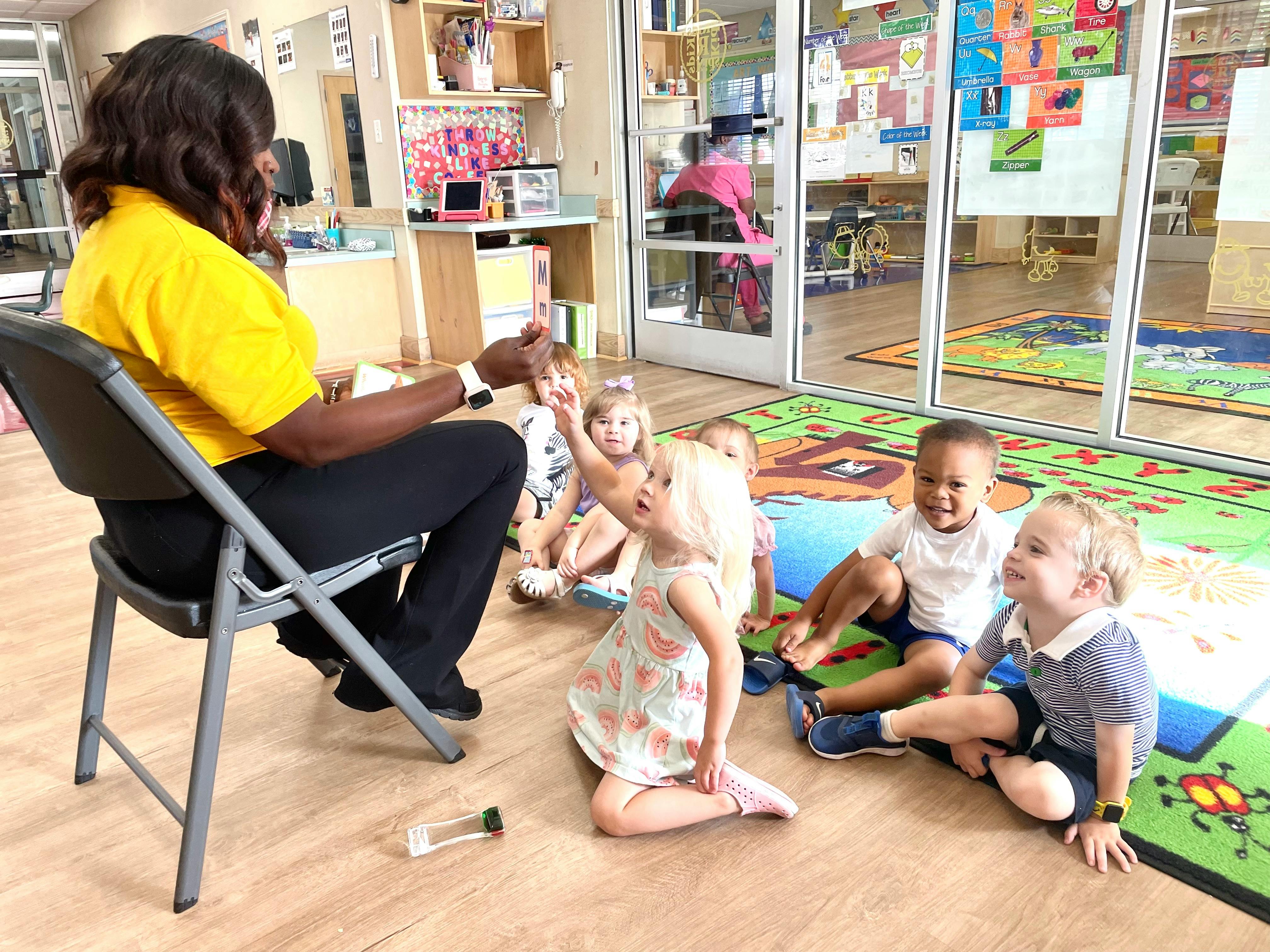 Person sitting in a chair with multiple children sitting on the floor