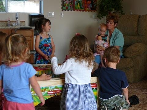 Adult holding a baby with children gathered around a table