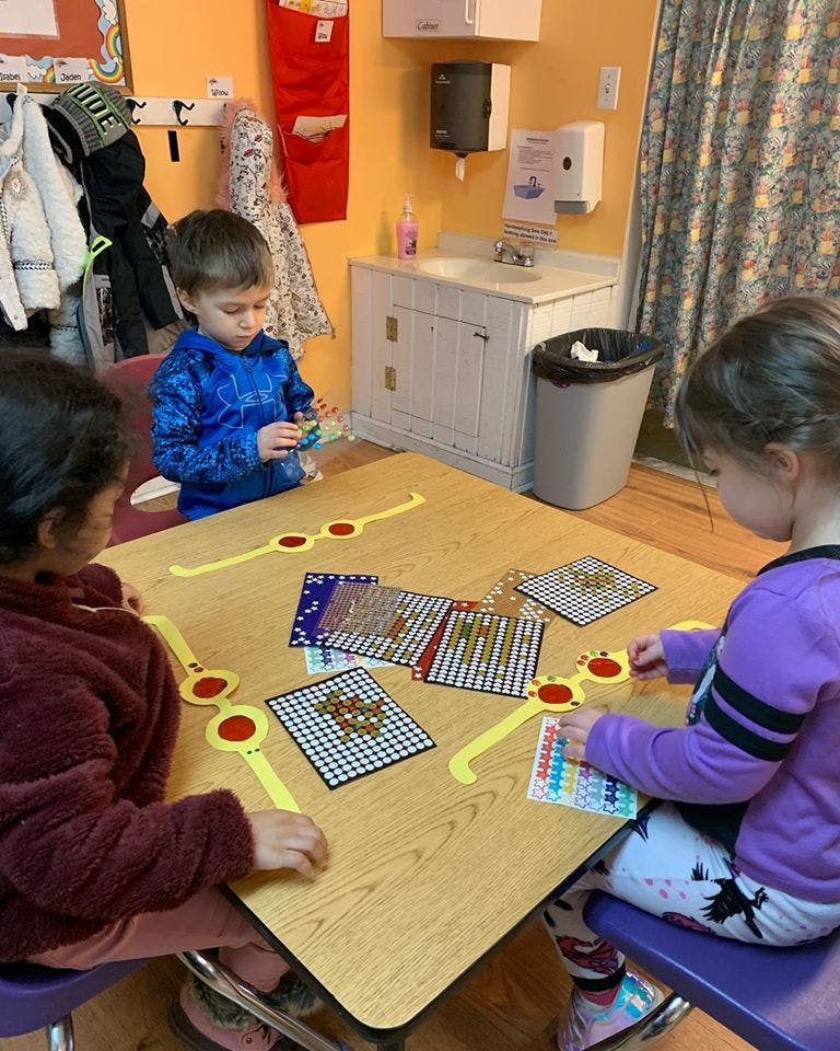 Three children playing with learning games at a table