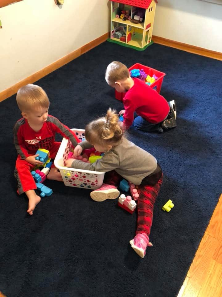 Three children playing with toys on a blue rug