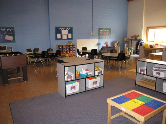 Classroom with round tables and chairs, foosball table, and storage shelves