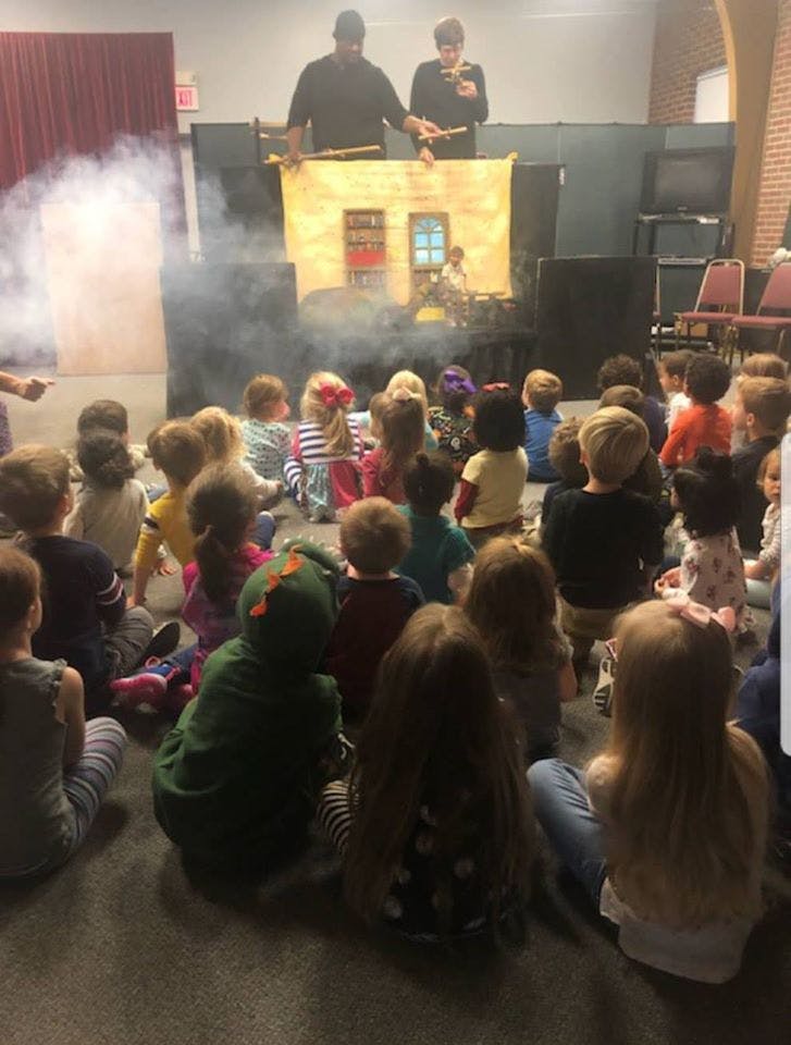 Children watching two people perform a puppet show with smoke effects