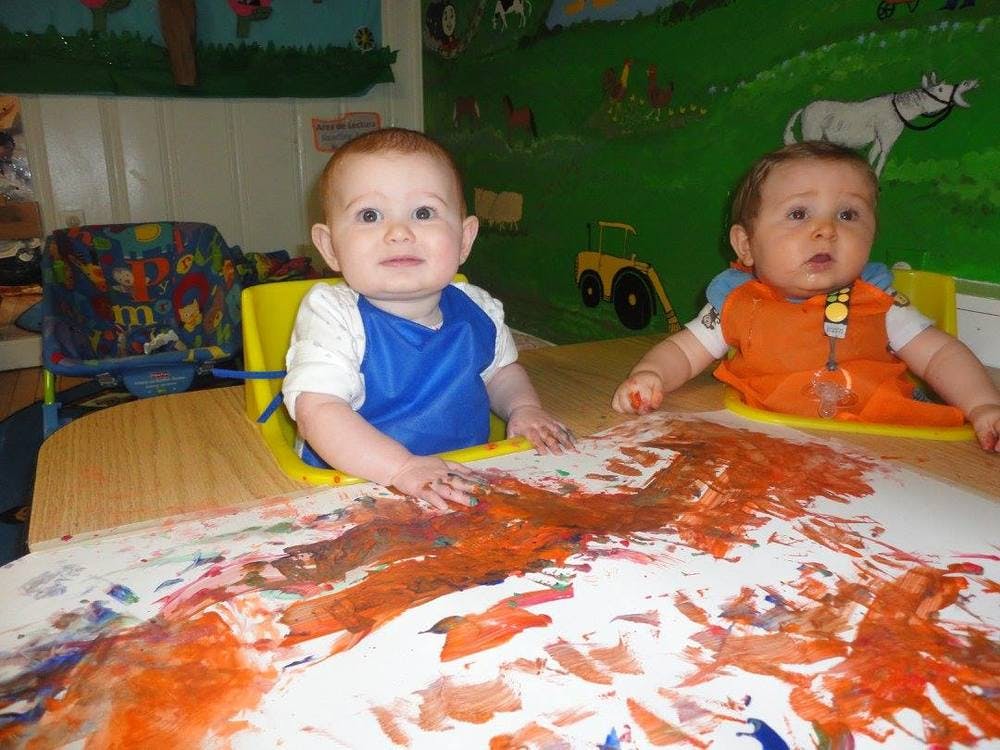 Two babies in high chairs finger painting