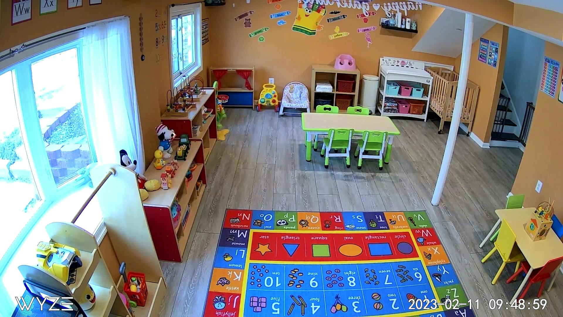 Playroom with colorful rug, small tables and chairs, and shelves with toys