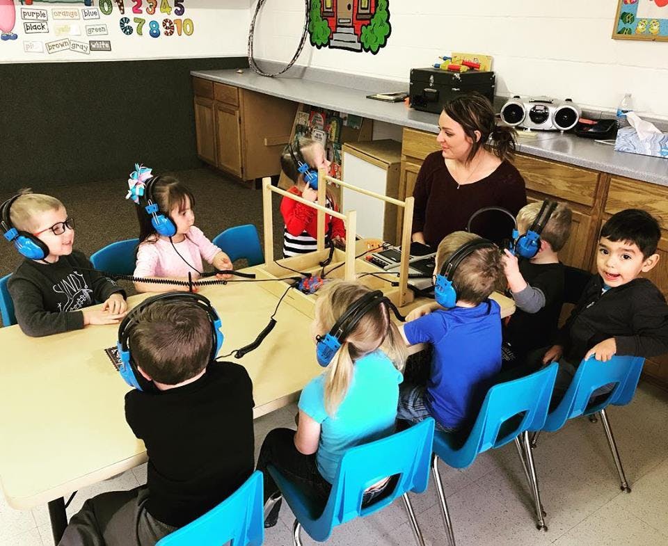 Adult and children wearing headphones in a classroom