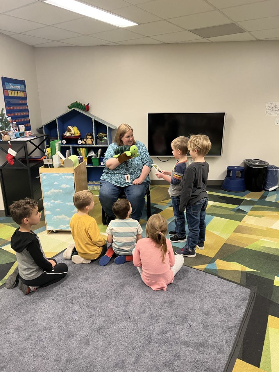 Adult using a puppet to interact with children in a classroom