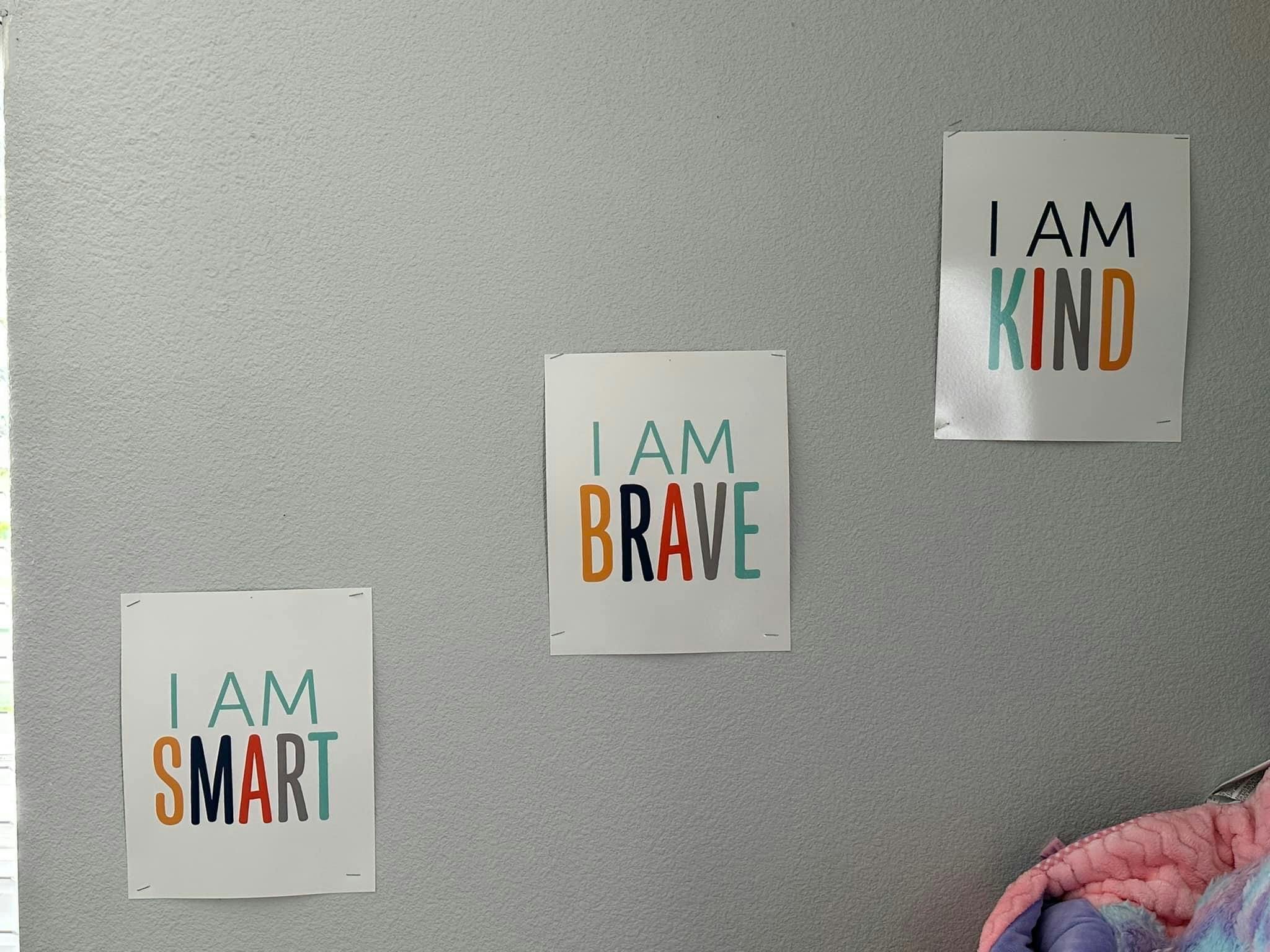 Three posters on a wall with text "I AM SMART", "I AM BRAVE", and "I AM KIND"