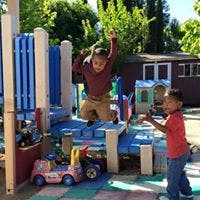 Child jumping from playground structure while another child watches