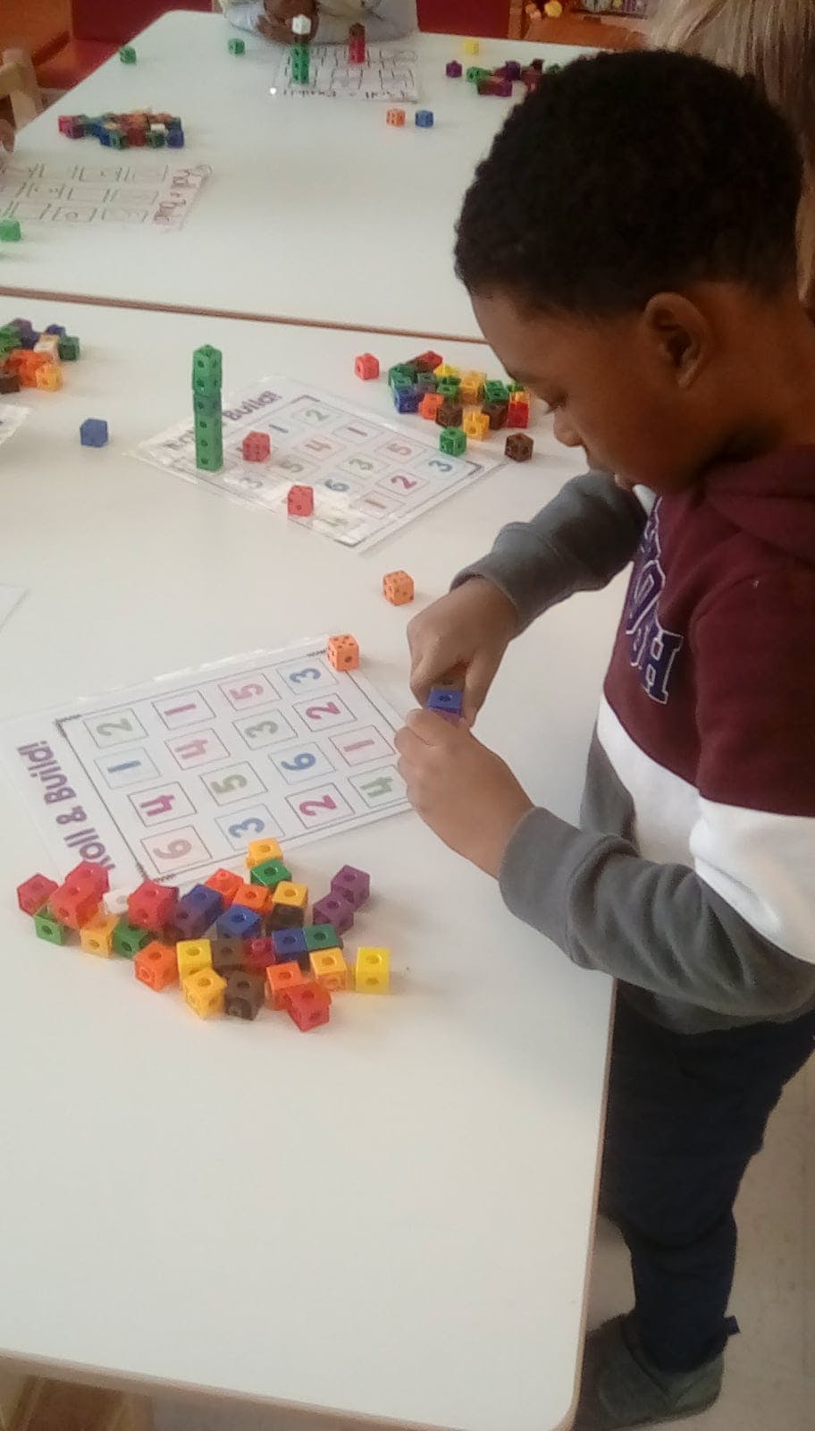 Child playing with colorful connecting cubes and a number grid