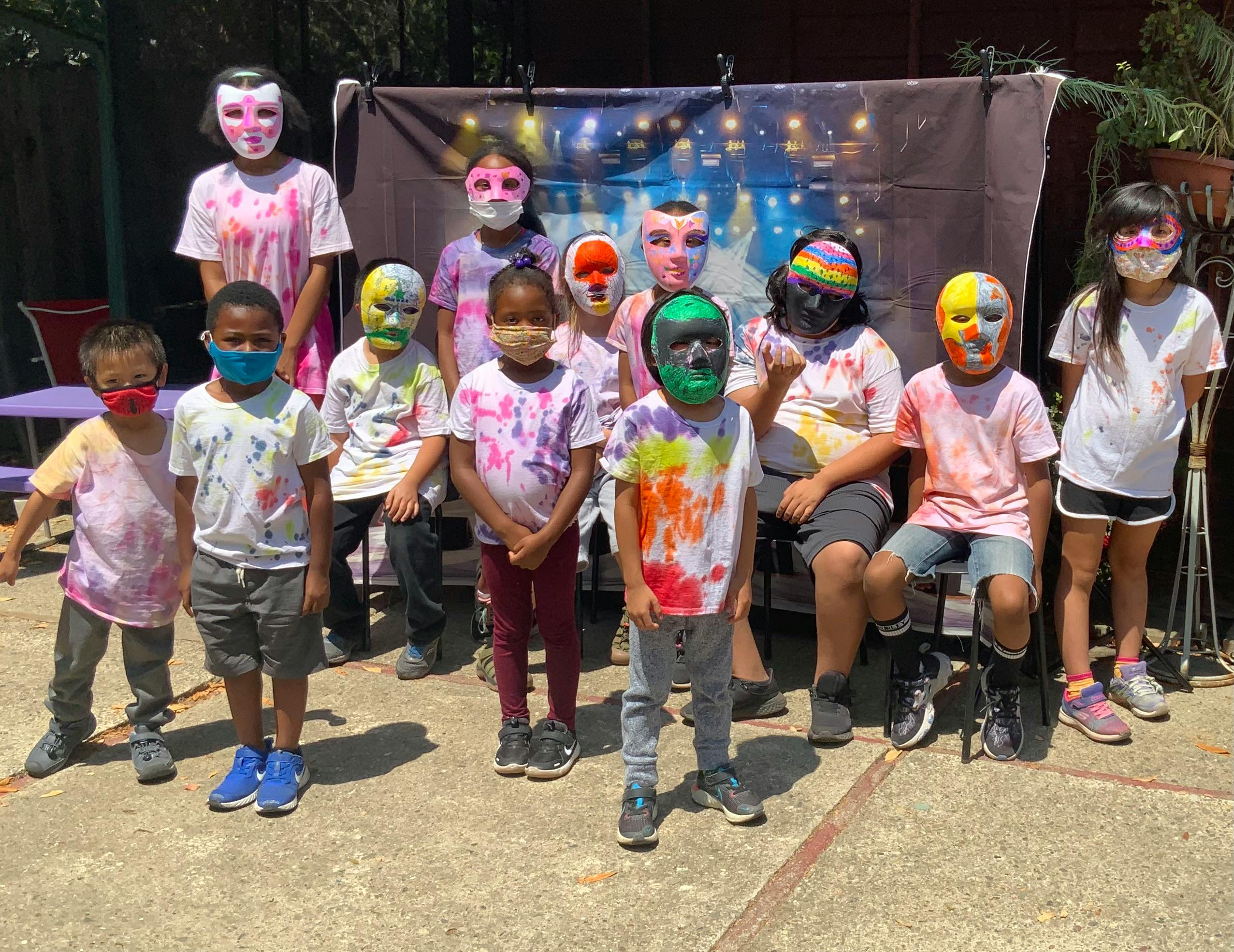 Group of children and adults wearing masks and tie-dye shirts