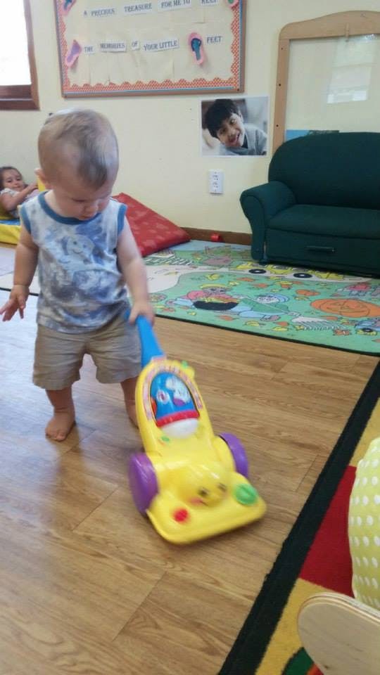 Child pushing a toy vacuum cleaner