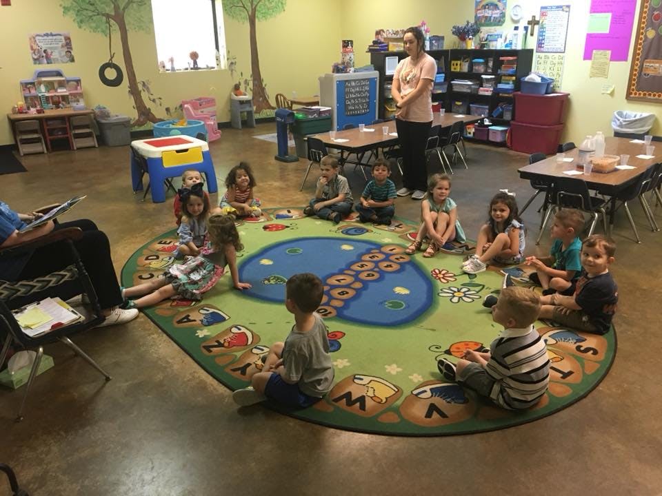 Adults and children sitting on a rug in a classroom