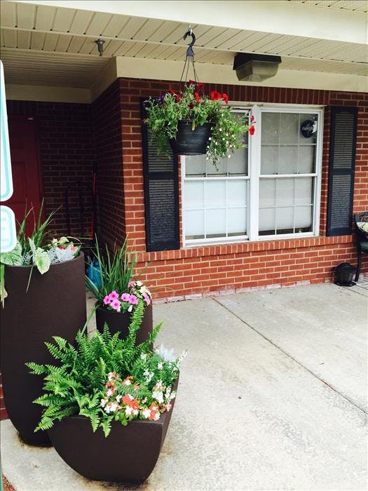 hanging flower basket and three large planters with plants and flowers on a porch