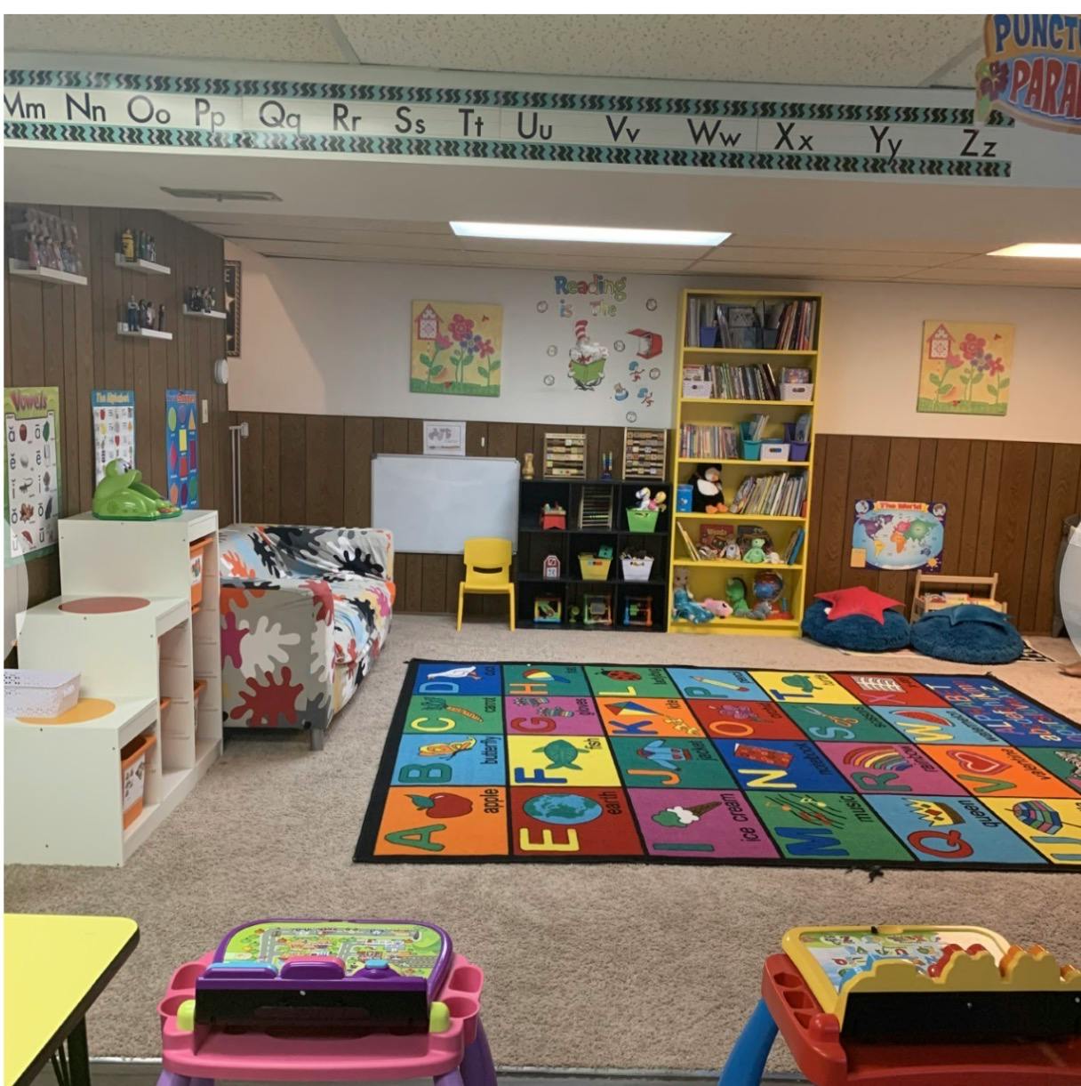 Classroom interior with an alphabet rug, children's furniture, and wall posters