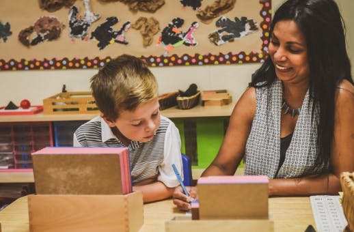 Adult and child at a table with blocks and a pen