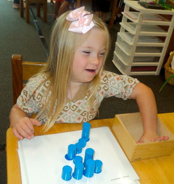 Child playing with blue blocks and a wooden box at a table