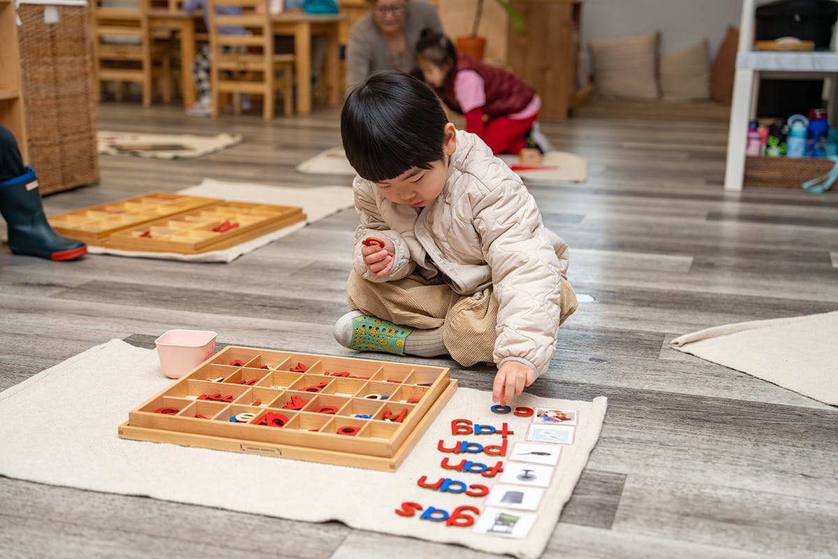 Child playing with letter tiles on the floor