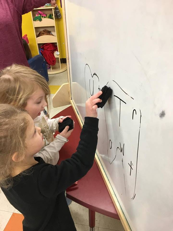 Two children erasing a whiteboard