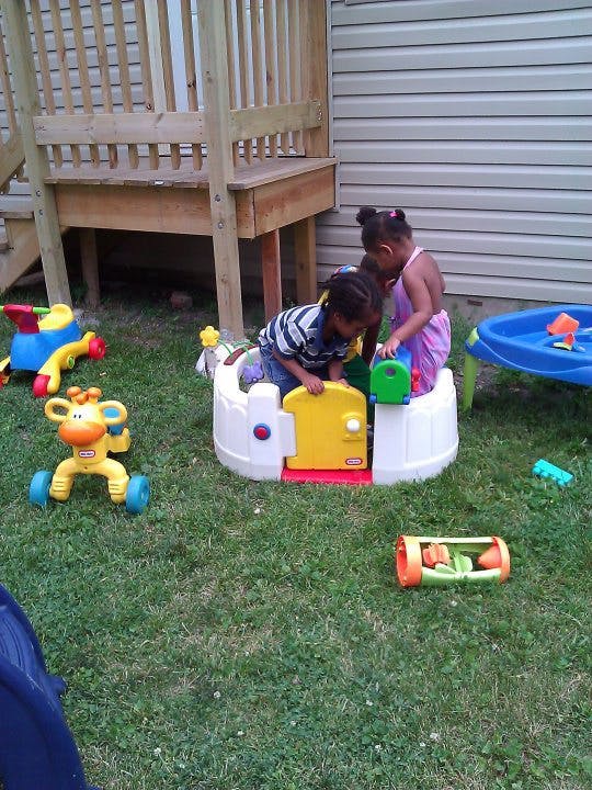 Two children playing with toys in a grassy backyard