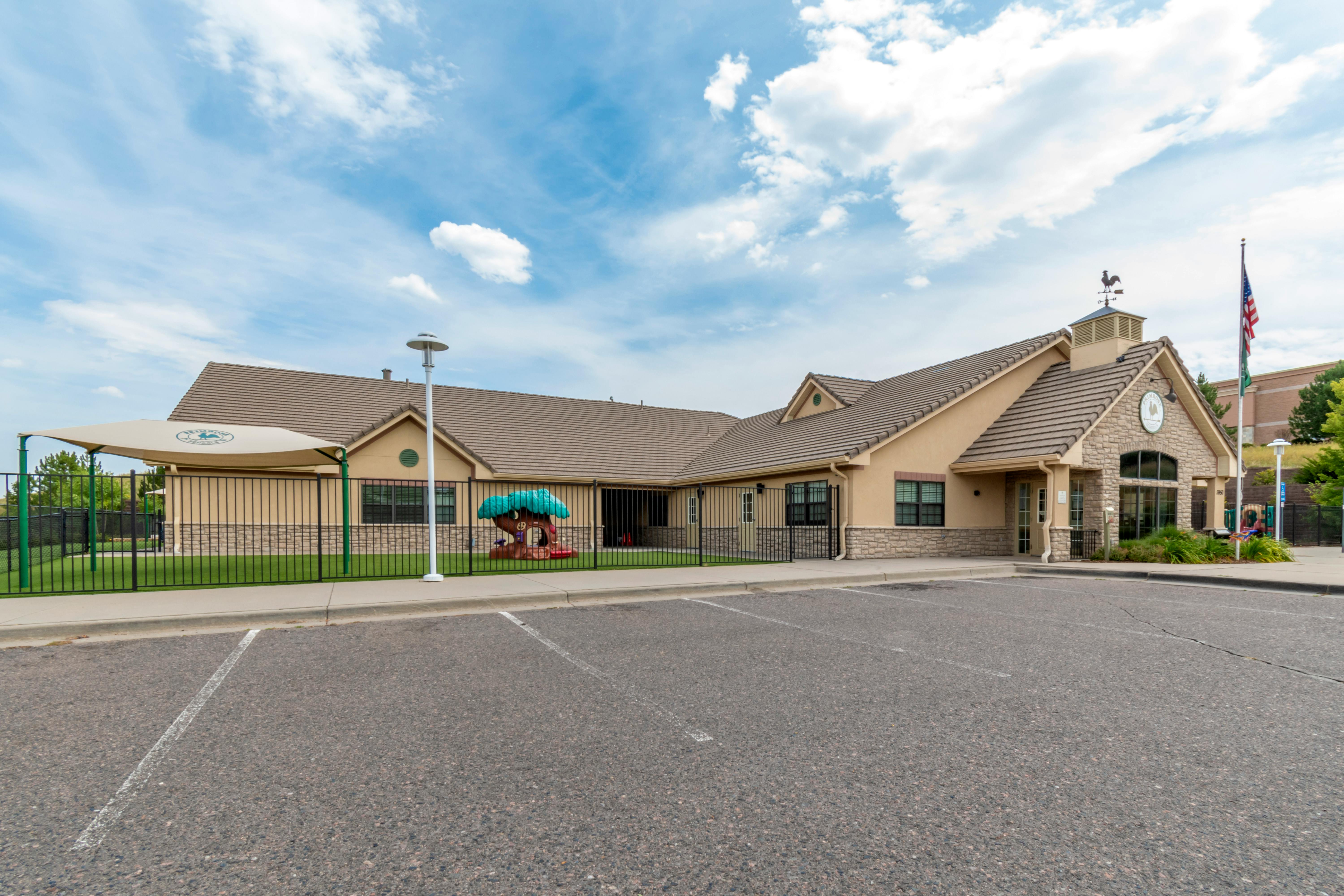 Exterior view of a school building with a playground and parking lot
