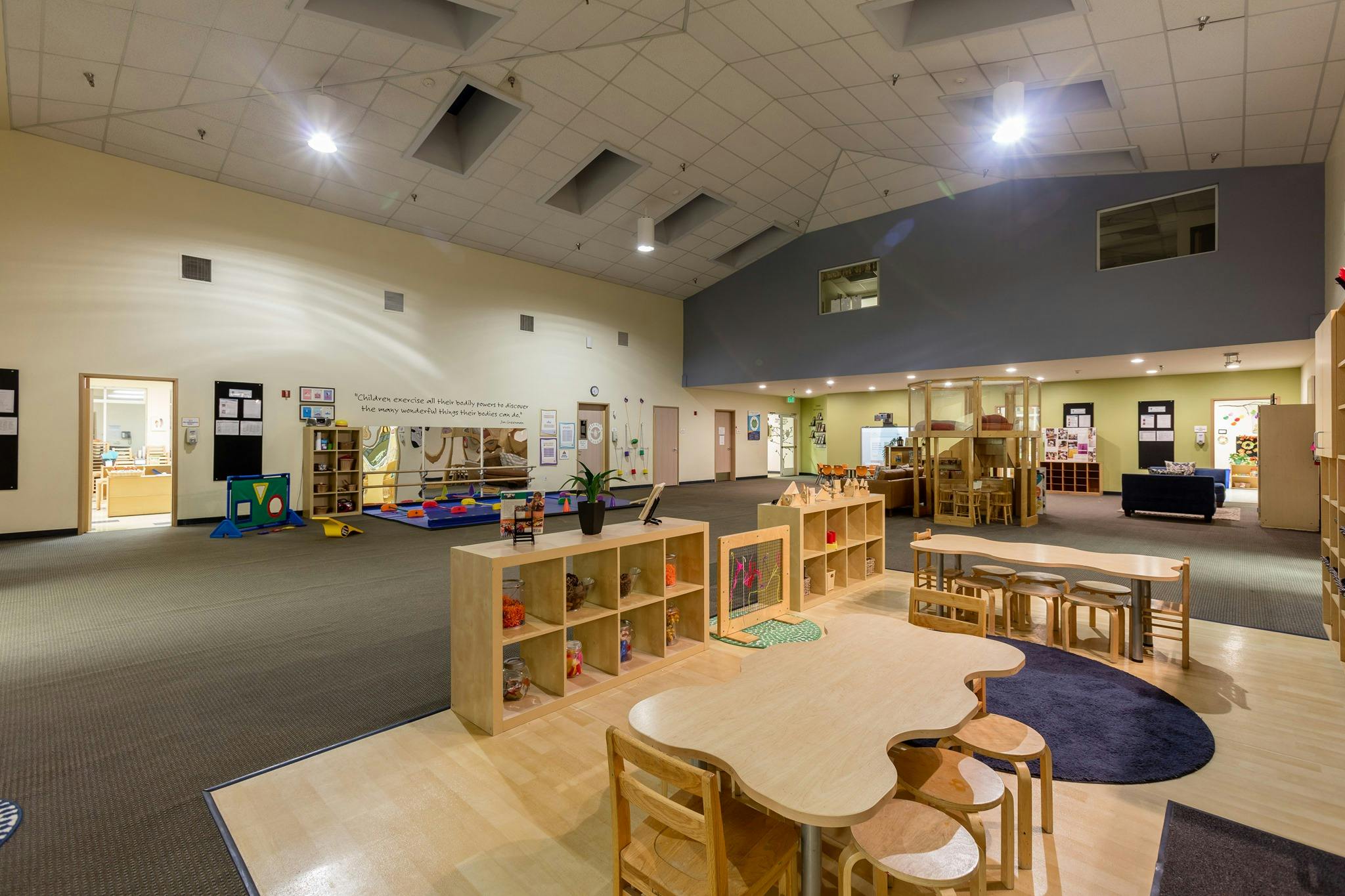 Large open room with tables, chairs, and shelves in a classroom setting
