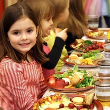 Child smiling at a table with food