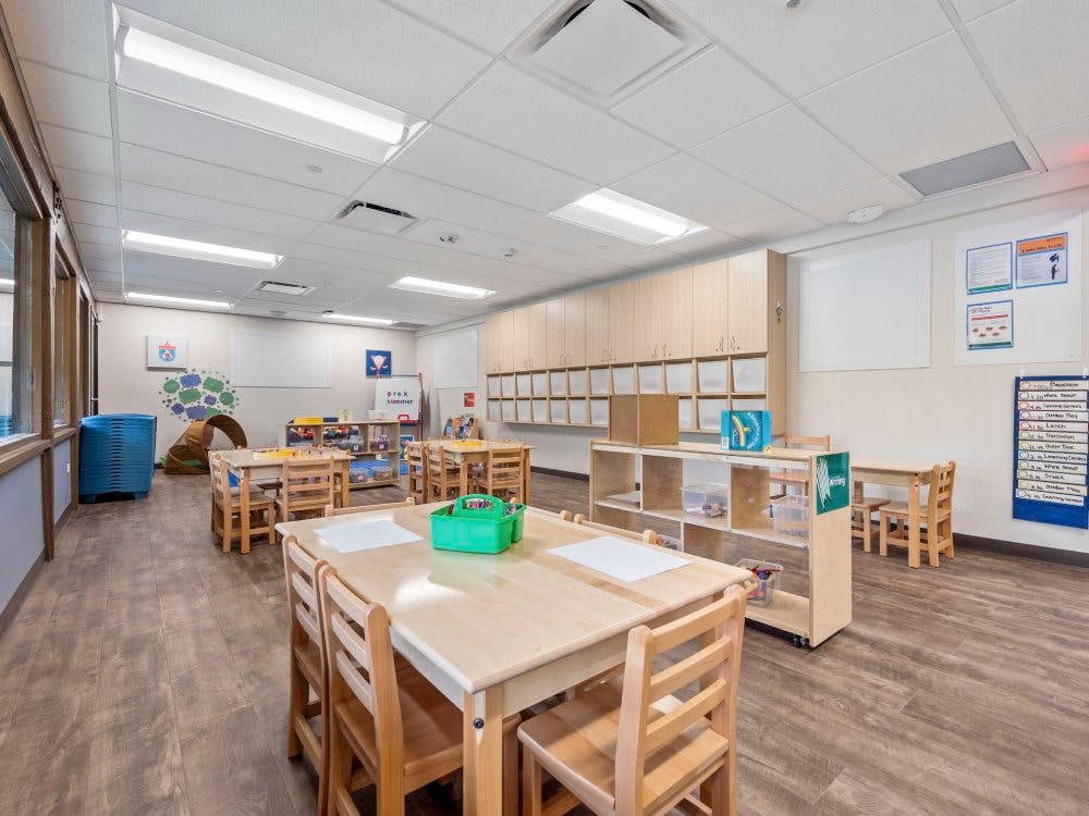 Empty children's classroom with small wooden tables and chairs