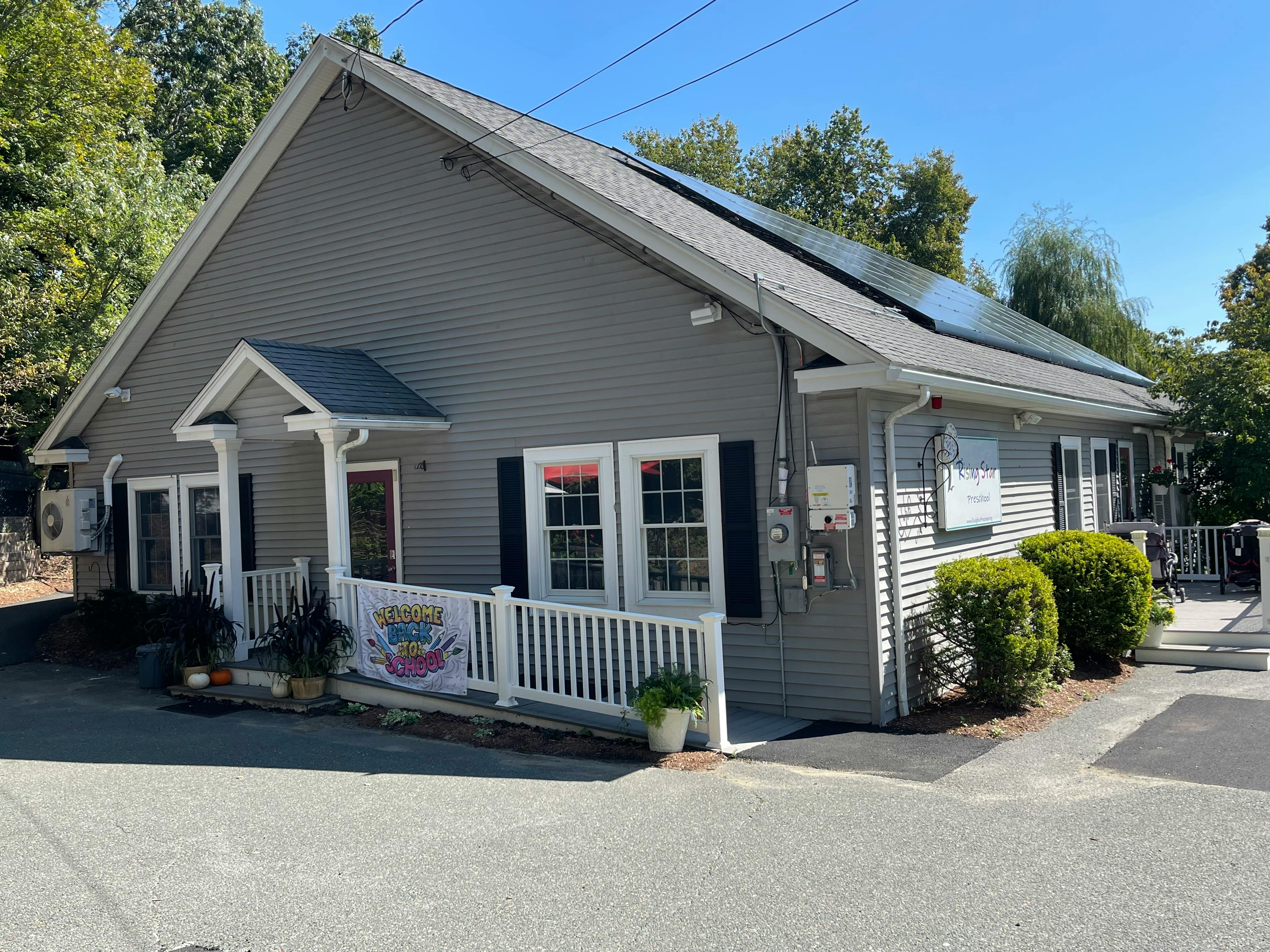 Gray building with white porch railing and solar panels on the roof