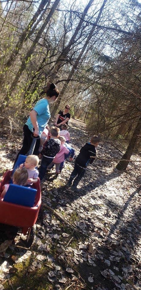 Adult pulling a wagon with children in a wooded area