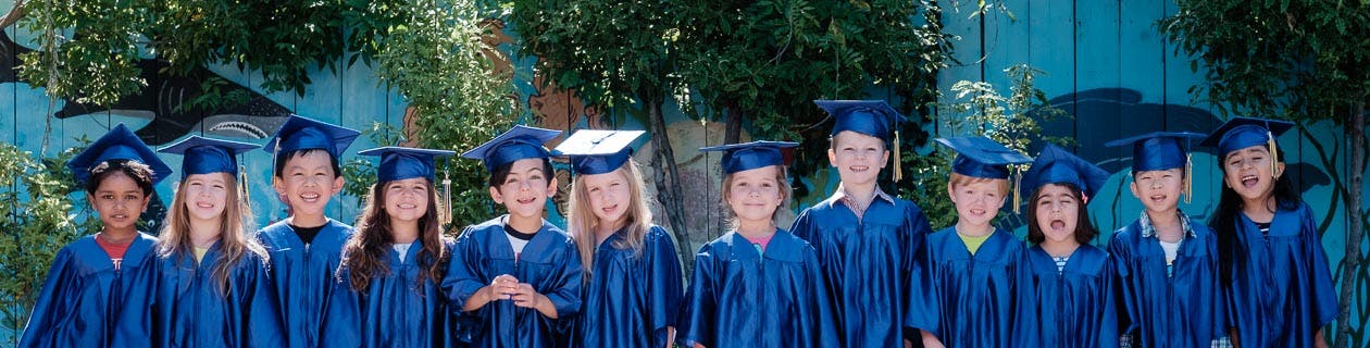 Group of children in blue graduation caps and gowns
