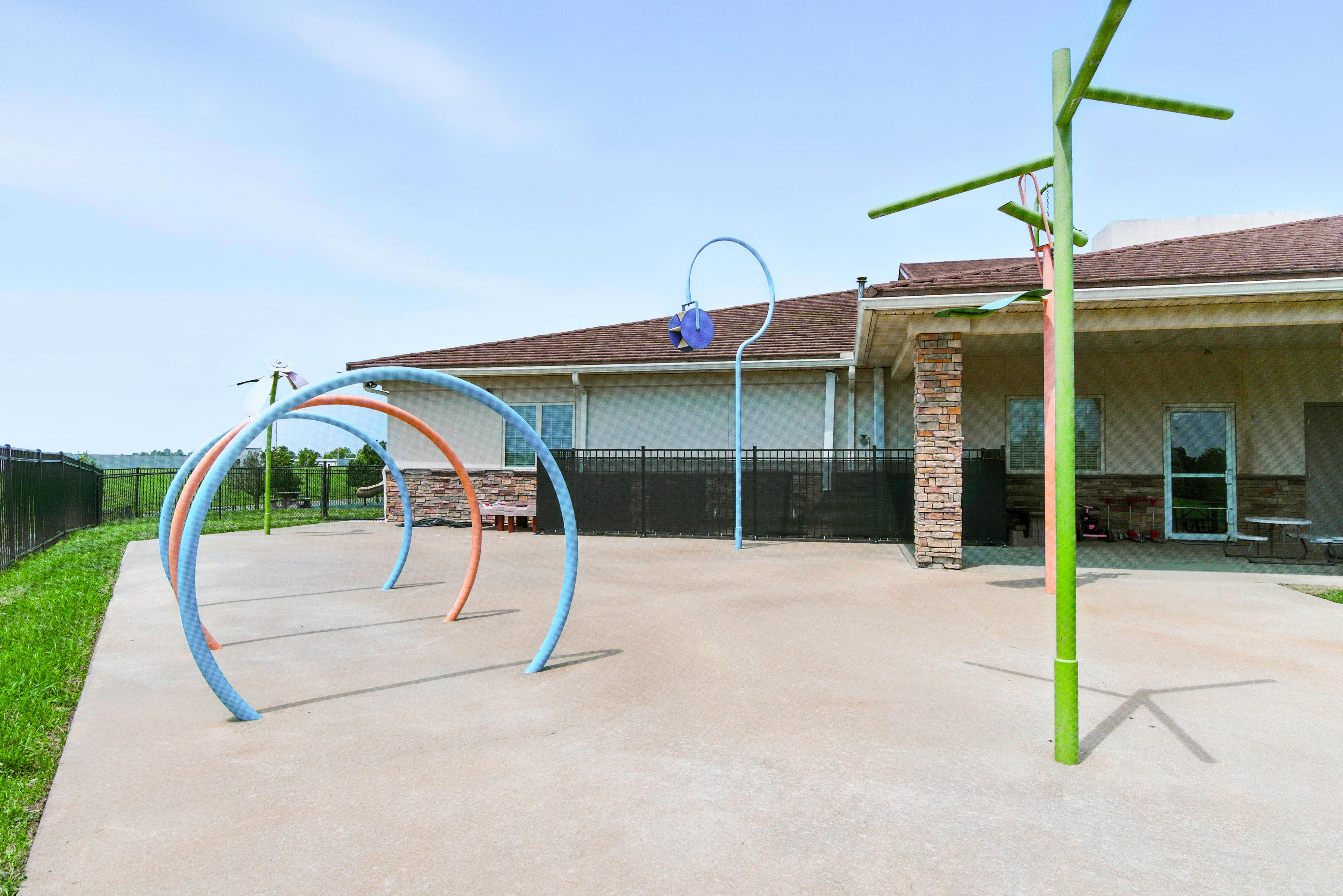 Outdoor splash pad with water arches and a green pole structure