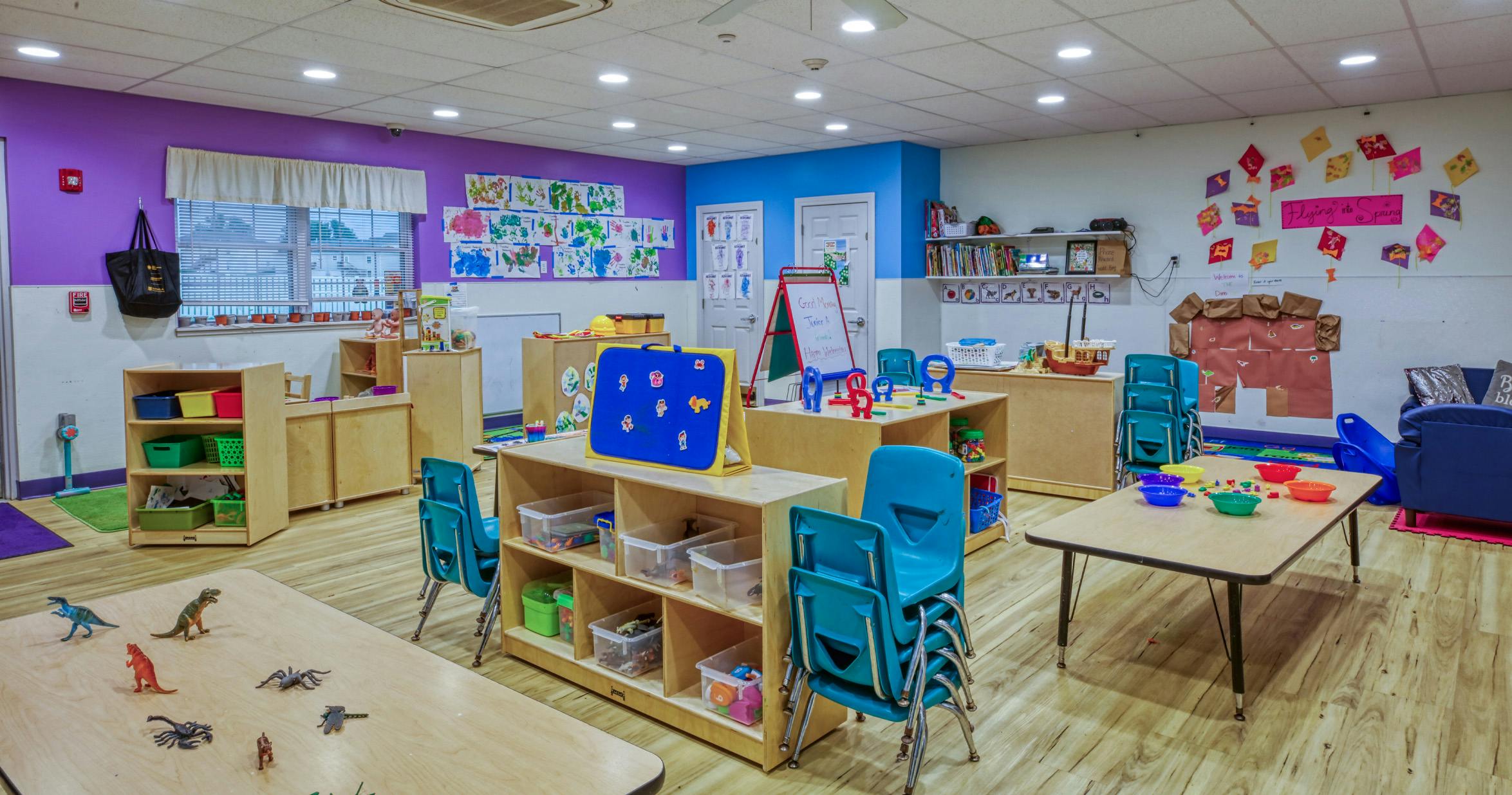 Colorful empty classroom with tables, chairs, and learning materials