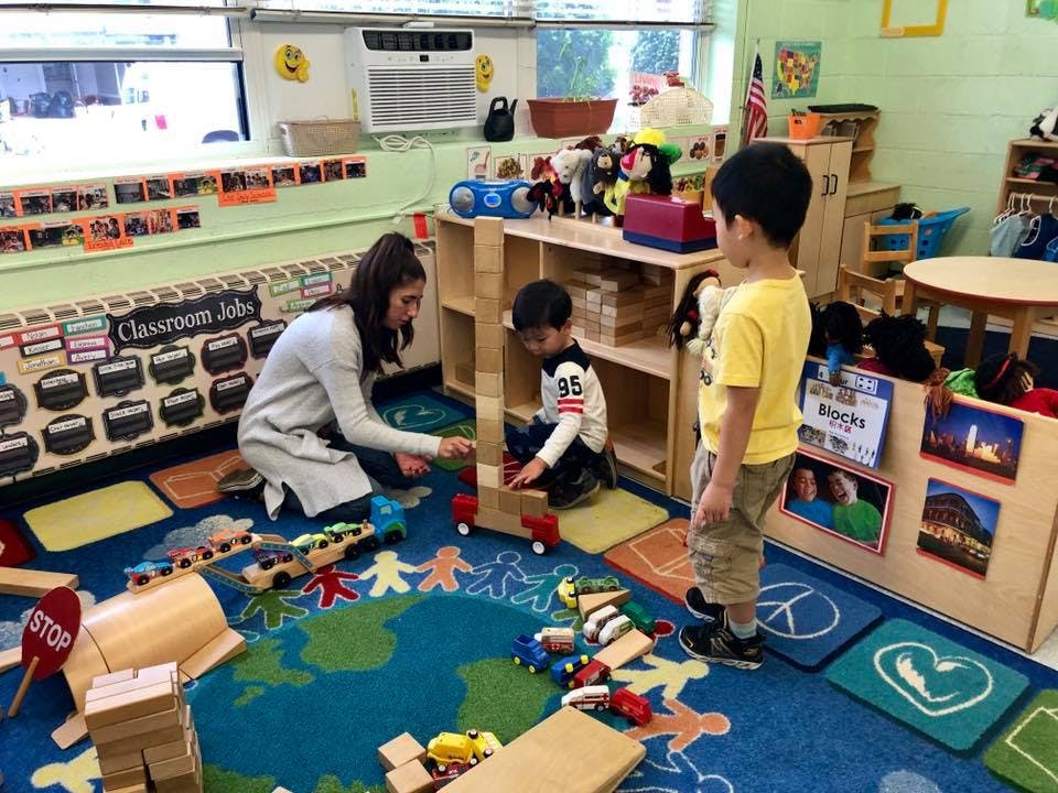 Adult and two children playing with blocks in a classroom