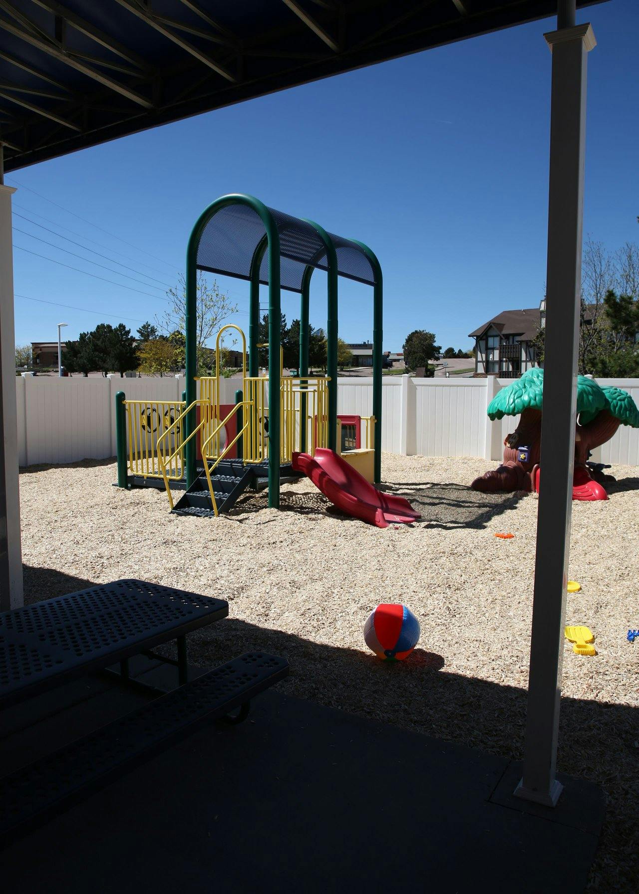 Playground with slides, climbing structure, and a ball on a sandy ground