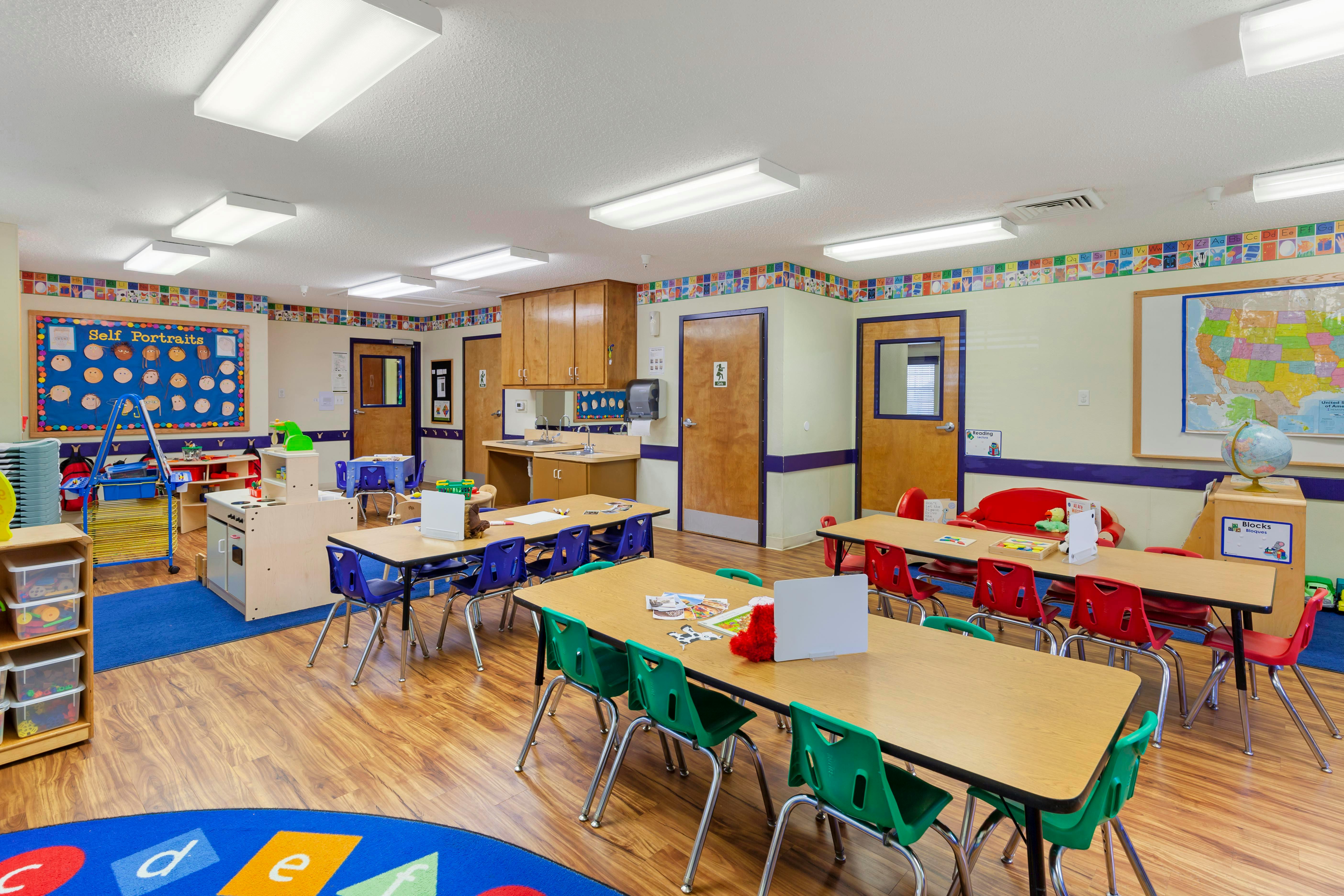 Colorful and organized classroom with tables and chairs, a sink, and a globe
