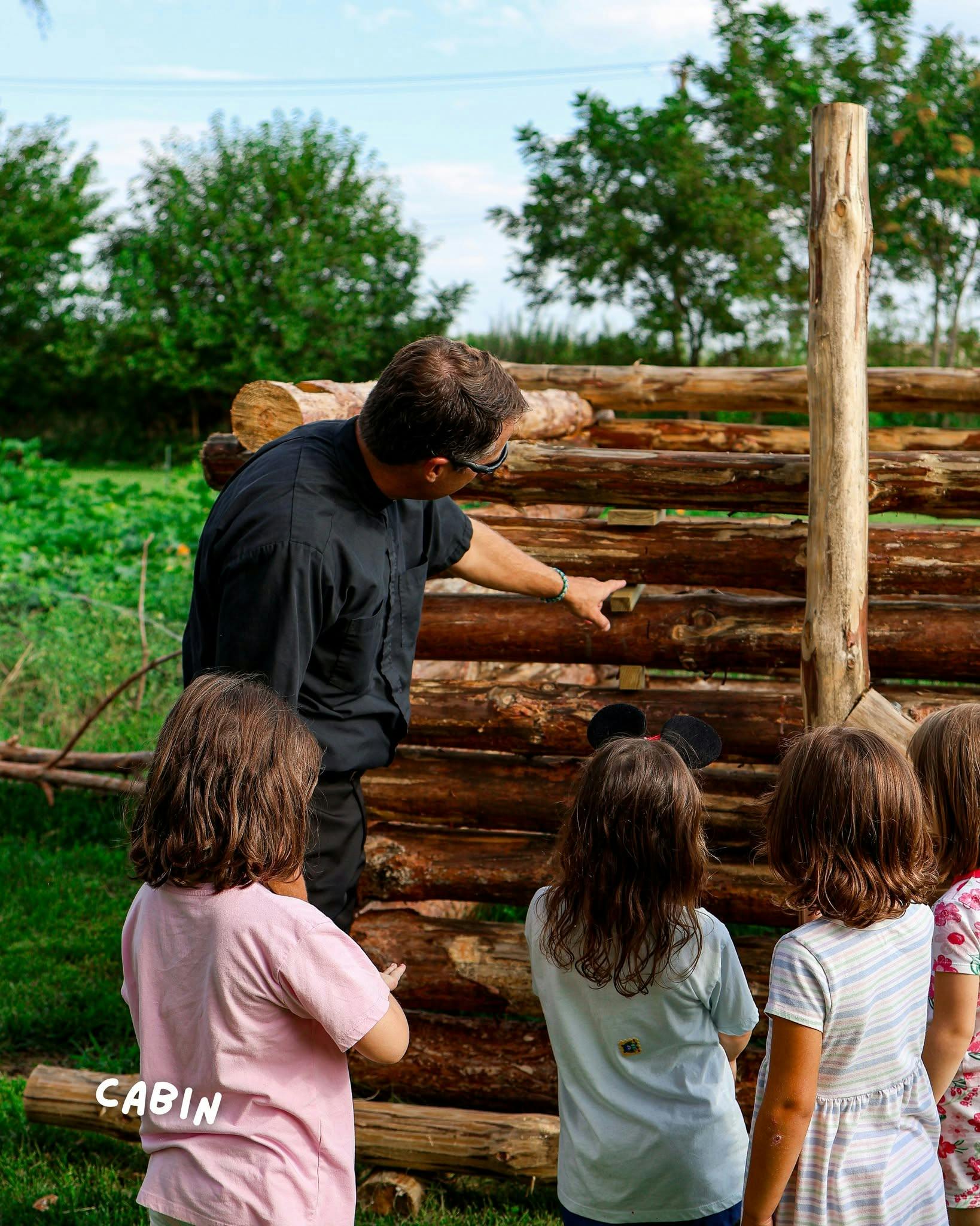 Person pointing at a partially built log structure for children