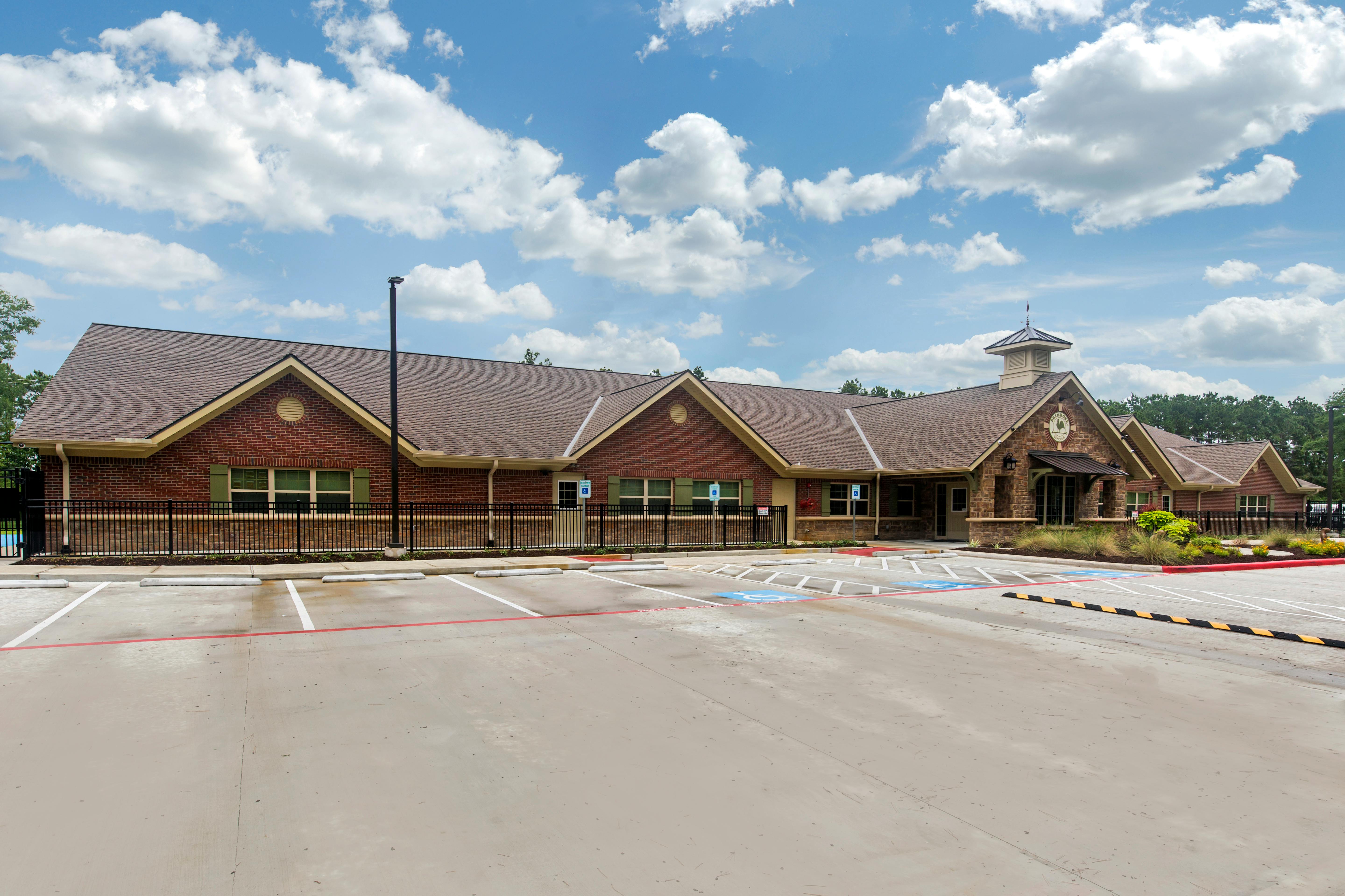 Brick building with a brown roof and a parking lot in front of it