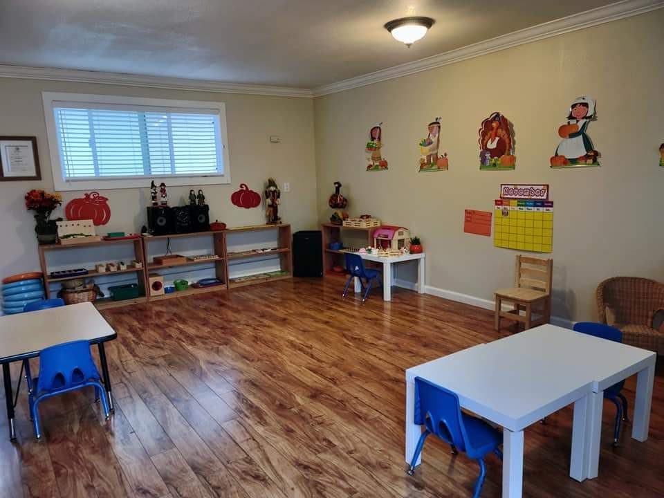 Classroom with small tables and chairs, shelves with learning materials, and wall decorations