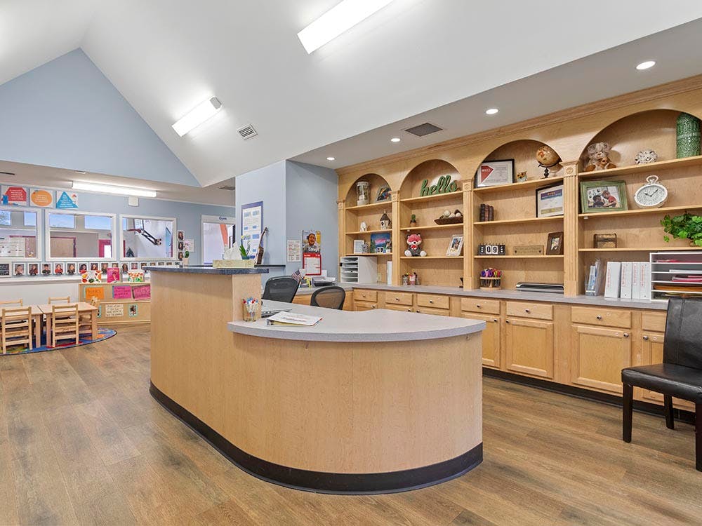 Reception desk in a childcare facility with a classroom visible in the background