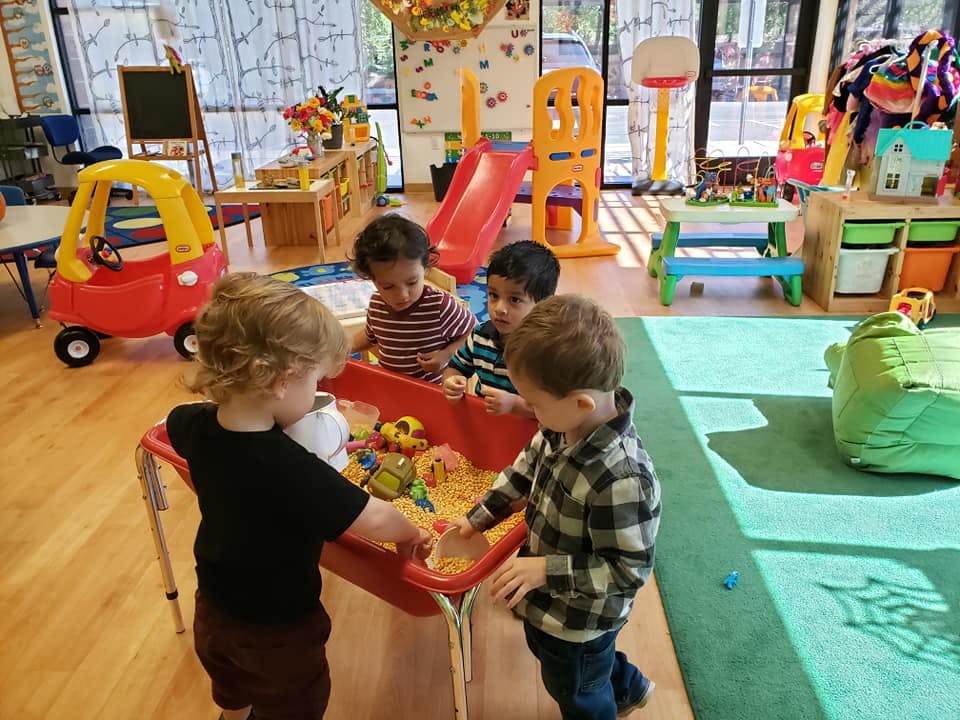 Four children playing at a sand table in a classroom